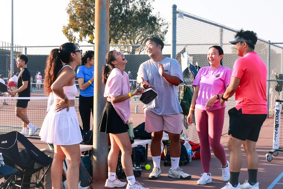 Groovy friends laughing together courtside at golden hour